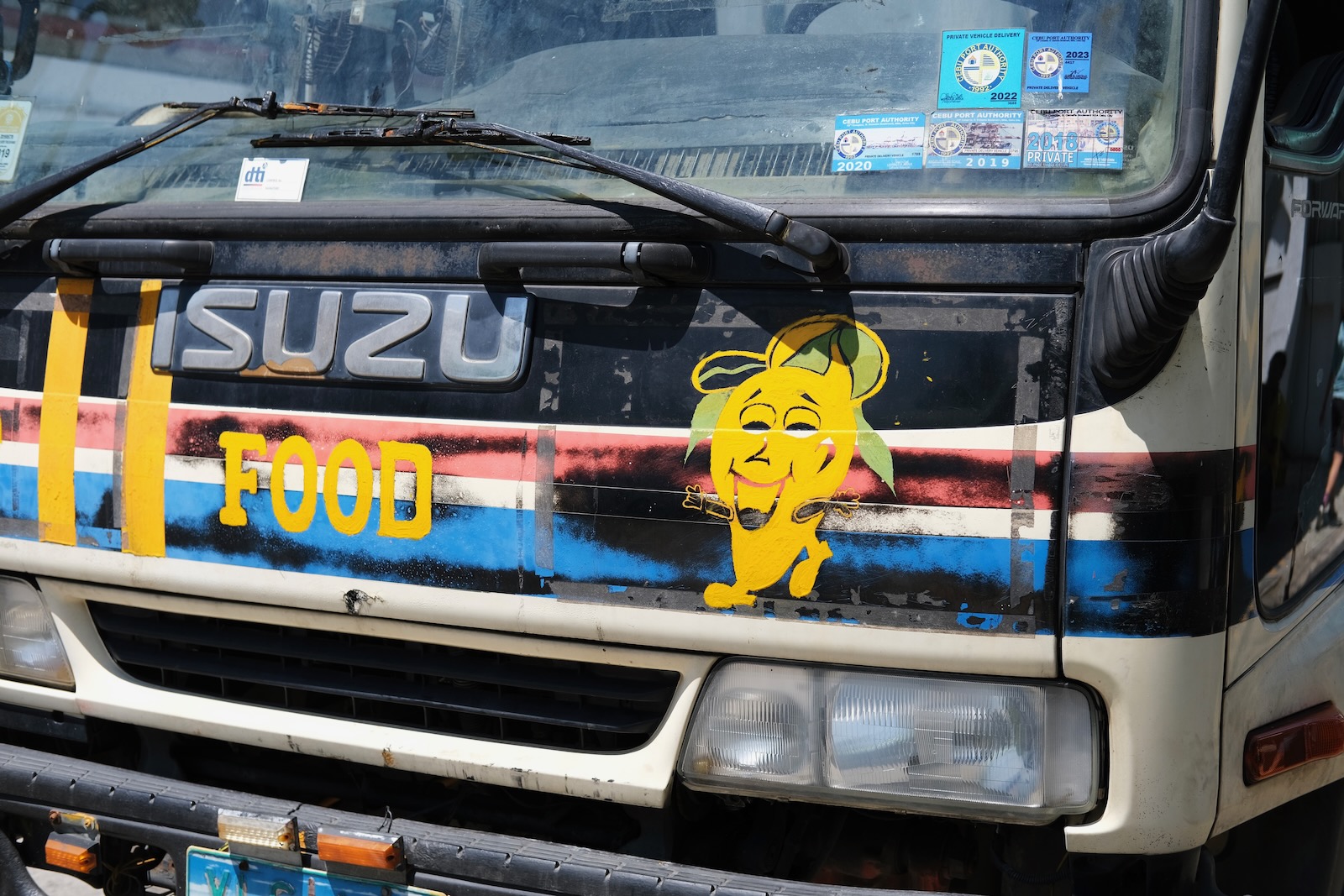 A truck painted with the word “Food” next to a smiling mango.