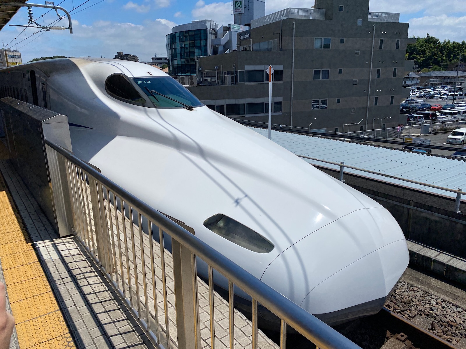 Elongated nose of a Shinkansen train pulling into the station.