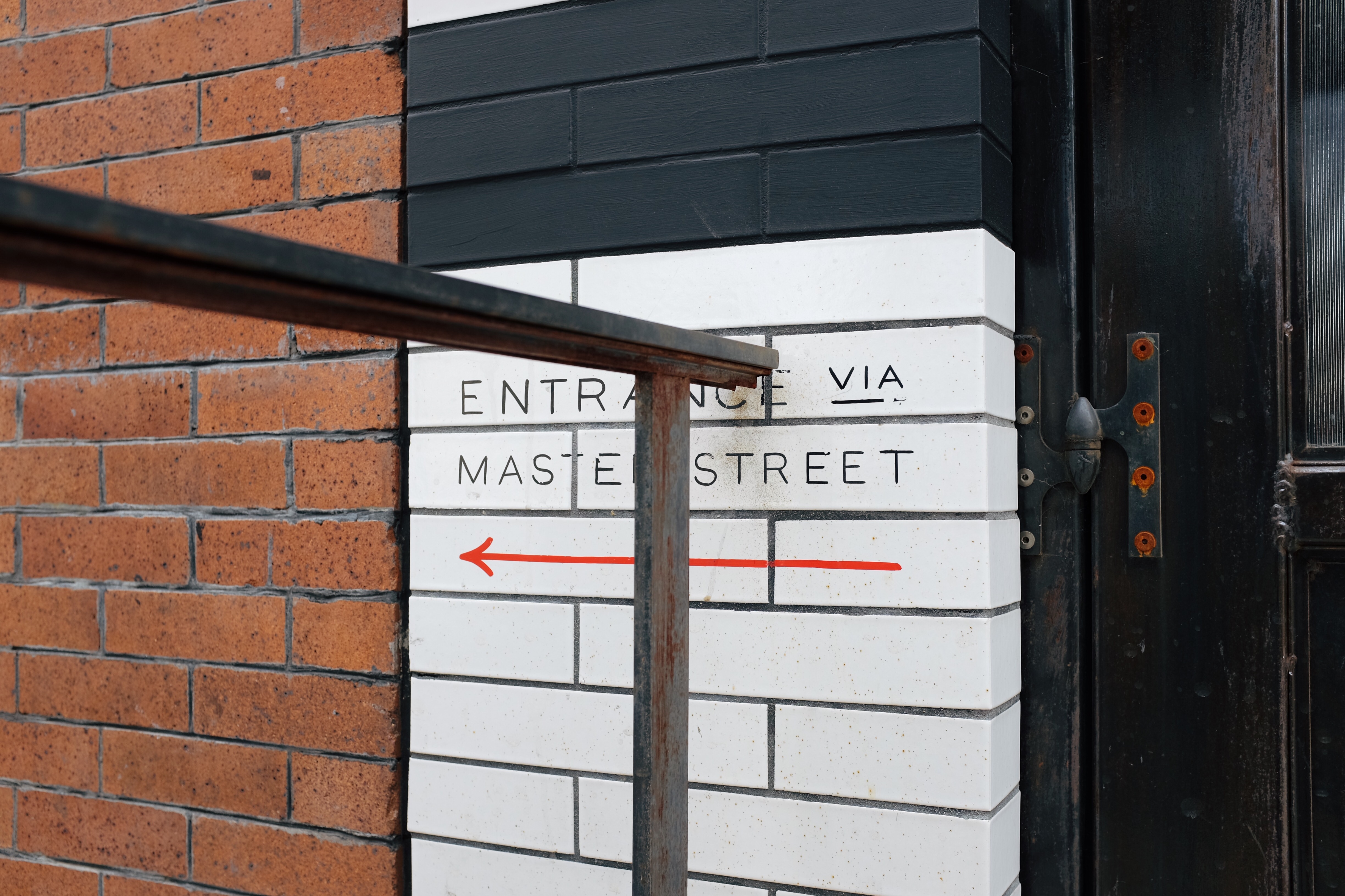 Right view of sign saying “Entrance via Master Street” cut off by hand rail